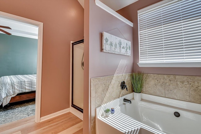 ensuite bathroom featuring connected bathroom, a shower stall, ceiling fan, a garden tub, and wood finished floors