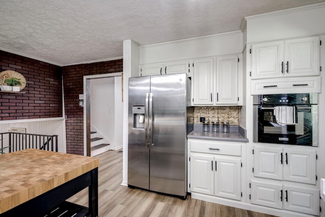 707 Oriole St, Aiken, SC 29803 - kitchen featuring stainless steel refrigerator with ice dispenser, oven, light wood finished floors, white cabinets, and brick wall