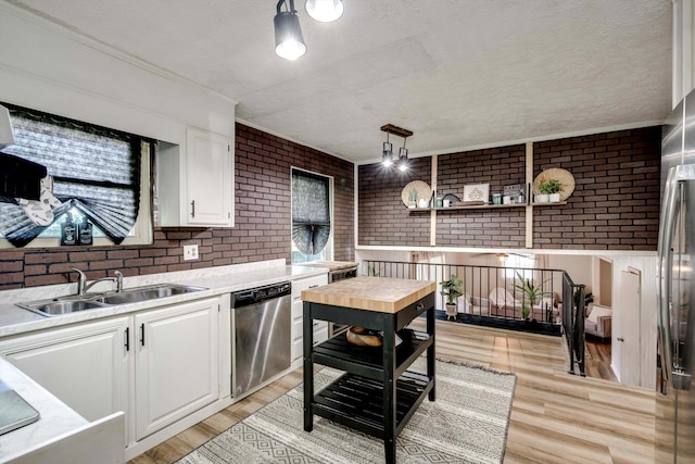 707 Oriole St, Aiken, SC 29803 - kitchen with brick wall, stainless steel dishwasher, white cabinets, a textured ceiling, and light wood-type flooring