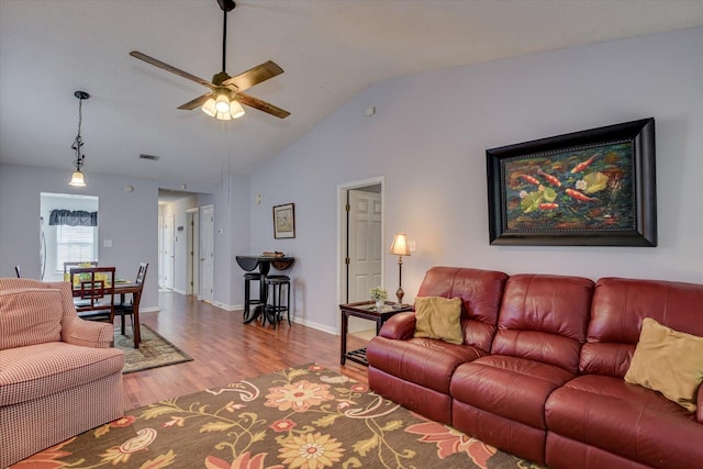 living area featuring visible vents, baseboards, ceiling fan, wood finished floors, and lofted ceiling