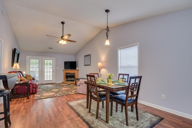 dining area with a fireplace, a ceiling fan, wood finished floors, lofted ceiling, and baseboards
