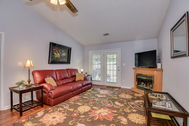 living area with visible vents, a ceiling fan, wood finished floors, and lofted ceiling