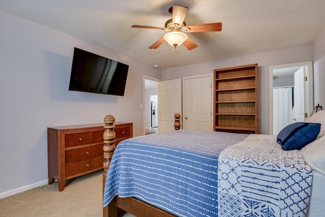 bedroom with baseboards, ceiling fan, light carpet, and a textured ceiling