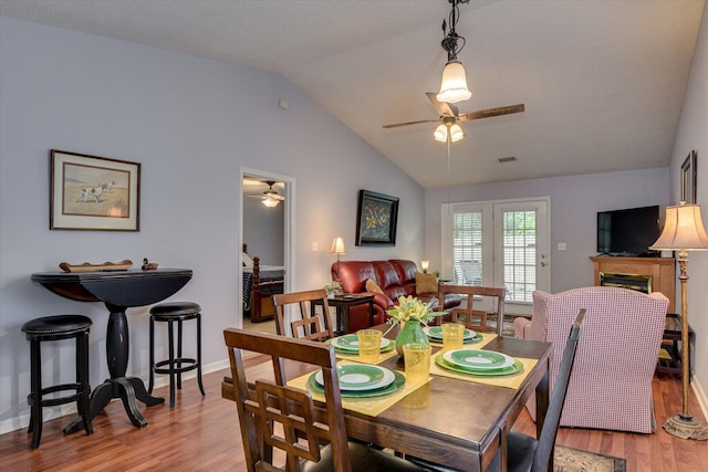 dining room featuring visible vents, wood finished floors, ceiling fan, and lofted ceiling