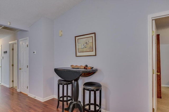 dining area featuring a textured ceiling, wood finished floors, baseboards, and visible vents