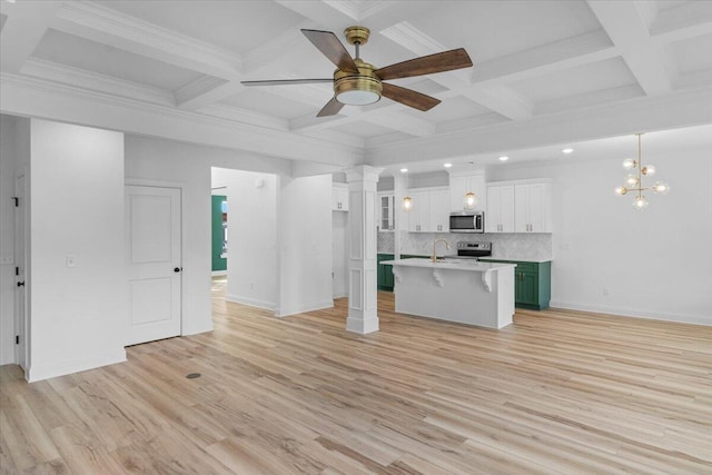 kitchen with a kitchen breakfast bar, backsplash, light wood finished floors, stainless steel microwave, and decorative columns