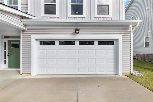 garage with concrete driveway and central air condition unit