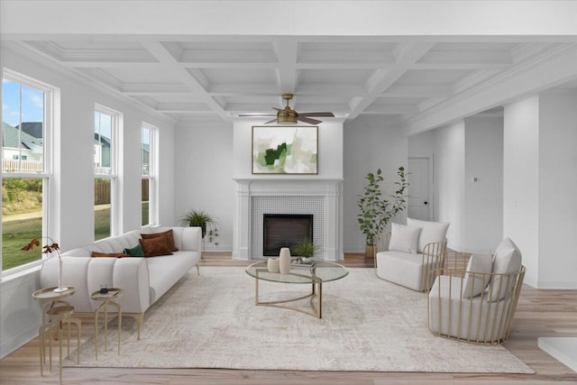 living area featuring ceiling fan, coffered ceiling, wood finished floors, a fireplace with flush hearth, and beam ceiling