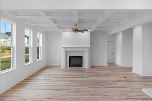 unfurnished living room featuring light wood-style floors, a ceiling fan, a tile fireplace, coffered ceiling, and beamed ceiling