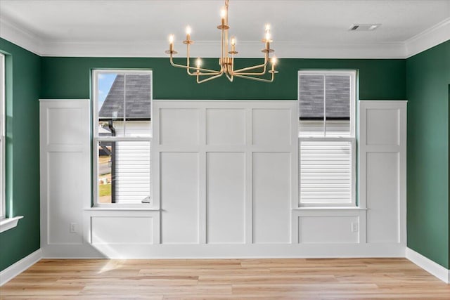 unfurnished dining area featuring light wood-style floors, visible vents, and ornamental molding