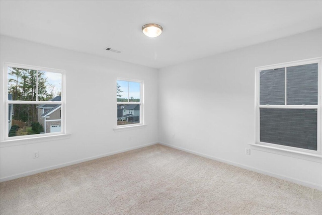 unfurnished room with carpet floors, visible vents, and baseboards