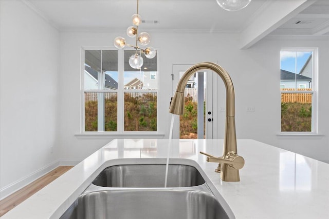 interior details featuring baseboards, ornamental molding, a sink, and pendant lighting