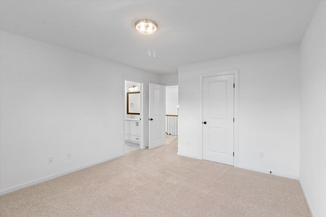 unfurnished bedroom featuring carpet floors, baseboards, and ensuite bath