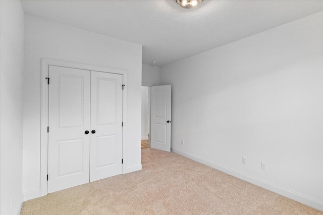 unfurnished bedroom with carpet floors, baseboards, and a closet