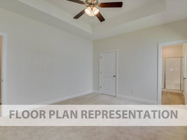 spare room with a raised ceiling, light carpet, and ceiling fan