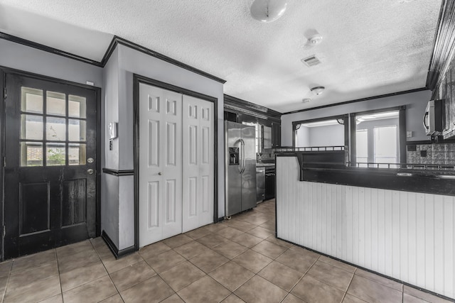 1736 Goshen Rd, Augusta, GA 30906 - kitchen featuring ornamental molding, stainless steel appliances, tile patterned floors, dark countertops, and a textured ceiling