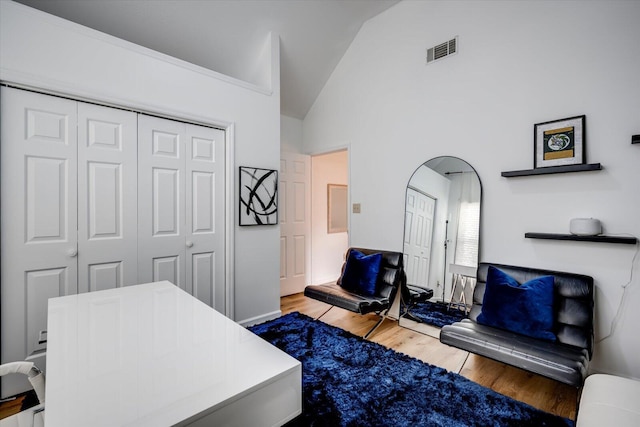 bedroom featuring visible vents, high vaulted ceiling, wood finished floors, a closet, and arched walkways