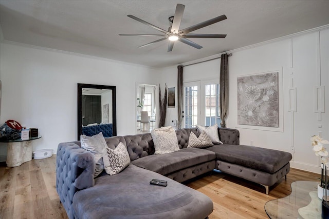 living area featuring ceiling fan, baseboards, wood finished floors, and crown molding