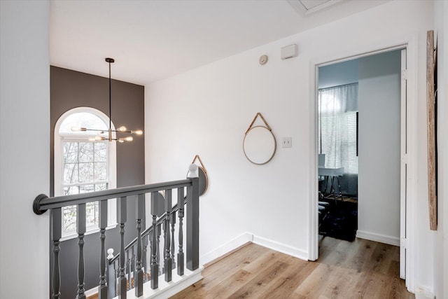 hallway featuring an inviting chandelier, wood finished floors, an upstairs landing, and baseboards