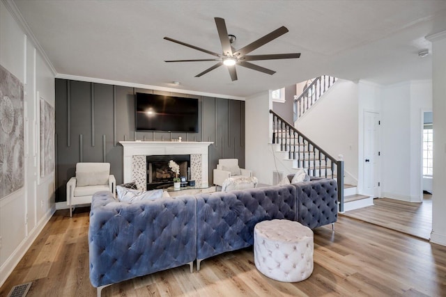 living area with crown molding, a decorative wall, a ceiling fan, and visible vents