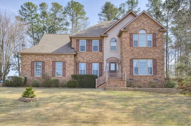 view of front of home featuring a front yard, brick siding, and roof with shingles