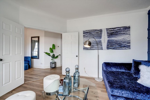 living area featuring baseboards, wood finished floors, and crown molding