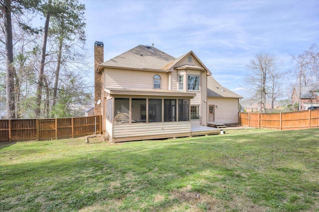 rear view of property featuring a yard, a fenced backyard, a chimney, and a sunroom