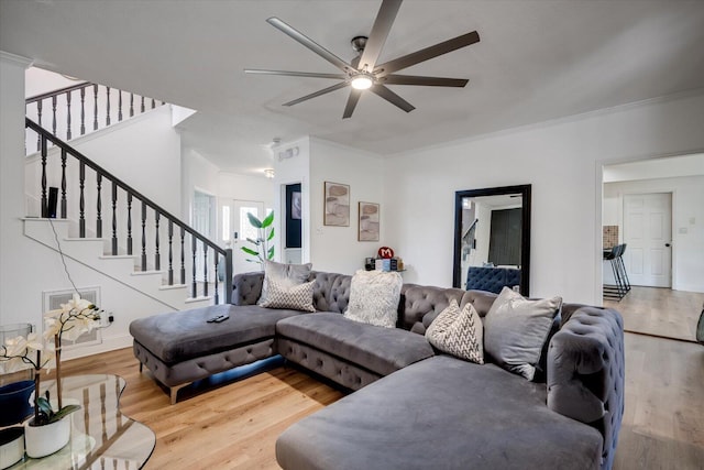 living area featuring a ceiling fan, crown molding, stairway, and wood finished floors