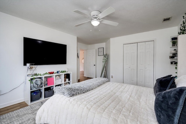 bedroom featuring visible vents, a ceiling fan, a textured ceiling, wood finished floors, and a closet