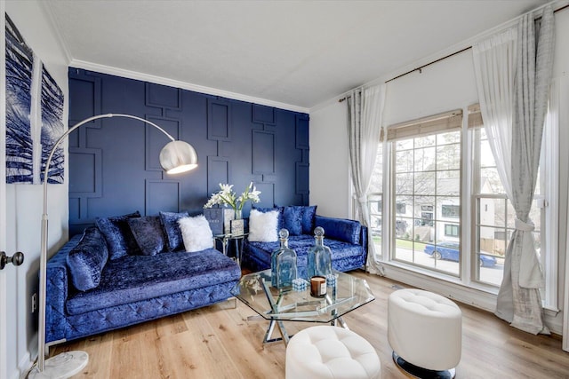 living room featuring a decorative wall, crown molding, and wood finished floors