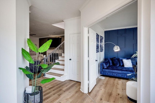 interior space featuring wood finished floors, stairs, ceiling fan, and ornamental molding