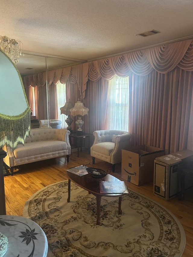 living area featuring plenty of natural light, a textured ceiling, wood finished floors, and visible vents
