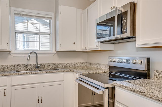 kitchen featuring appliances with stainless steel finishes, white cabinetry, plenty of natural light, and sink