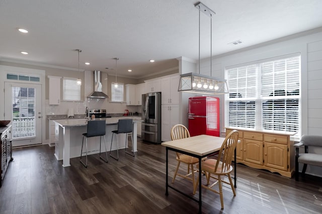 dining room featuring dark wood-style flooring, ornamental molding, visible vents, and a healthy amount of sunlight