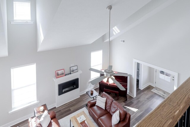 living room featuring high vaulted ceiling, a fireplace, a ceiling fan, visible vents, and wood finished floors