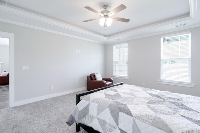 carpeted bedroom with crown molding, a tray ceiling, baseboards, and visible vents