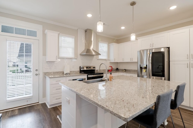 kitchen featuring white cabinets, wall chimney exhaust hood, a sink, a kitchen bar, and stainless steel appliances