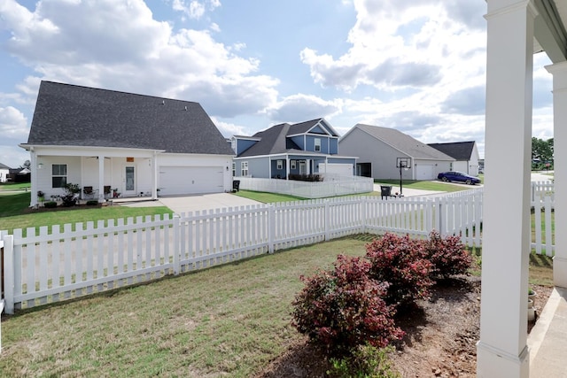 view of yard featuring an attached garage, concrete driveway, a residential view, and fence private yard
