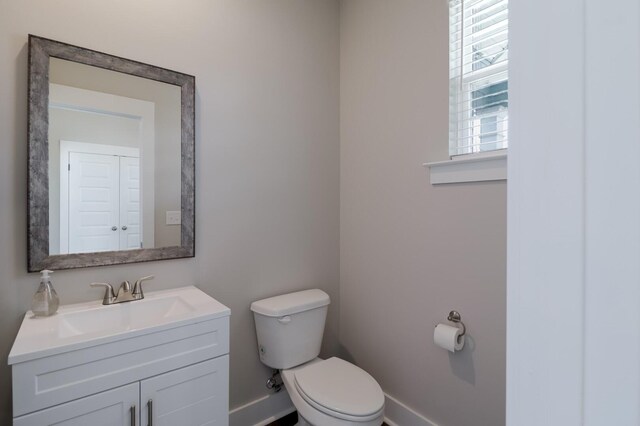 bathroom with toilet, baseboards, and vanity