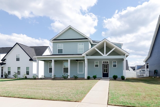 craftsman-style home with a porch, fence, and a front lawn
