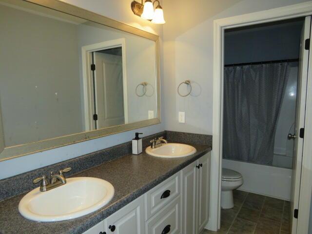 full bathroom with vanity, shower / tub combo, and toilet