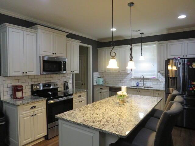 kitchen with white cabinets, sink, a kitchen island, and appliances with stainless steel finishes