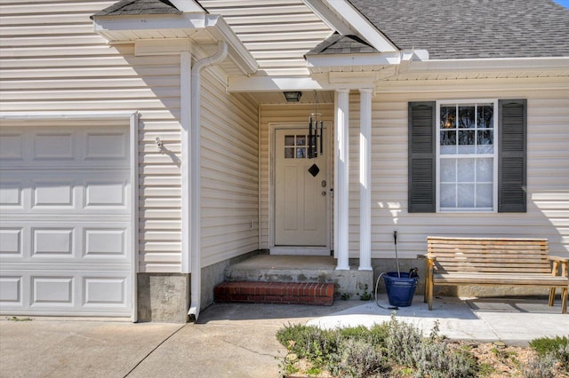 entrance to property with a garage and roof with shingles