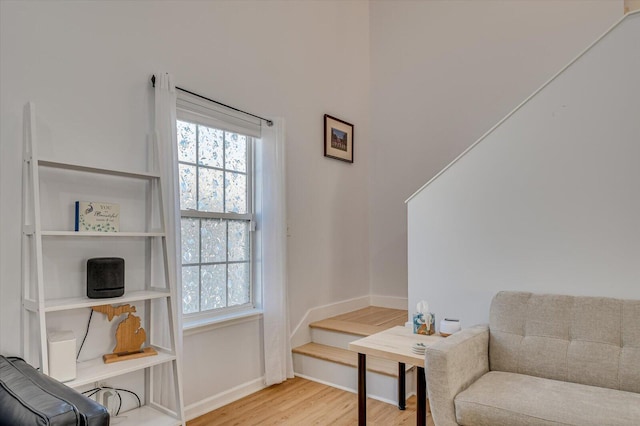 living area featuring stairs, baseboards, wood finished floors, and a healthy amount of sunlight