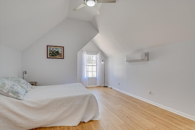 bedroom featuring light wood finished floors, baseboards, a ceiling fan, a wall mounted air conditioner, and vaulted ceiling