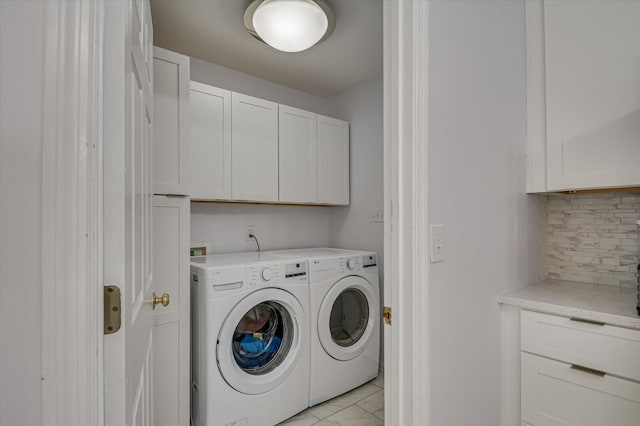 clothes washing area with washing machine and clothes dryer and cabinet space