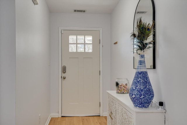 doorway with light wood-style flooring, visible vents, and baseboards