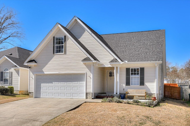 traditional home with concrete driveway, roof with shingles, fence, and an attached garage