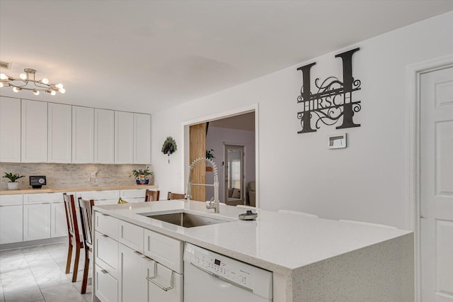 kitchen featuring backsplash, white cabinetry, a sink, light stone countertops, and dishwasher