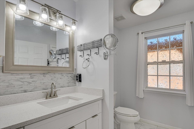 bathroom featuring toilet, visible vents, backsplash, and a wealth of natural light